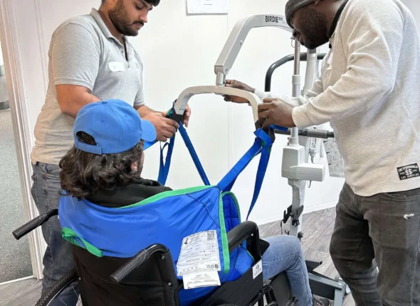 man being listed into a care home hoist