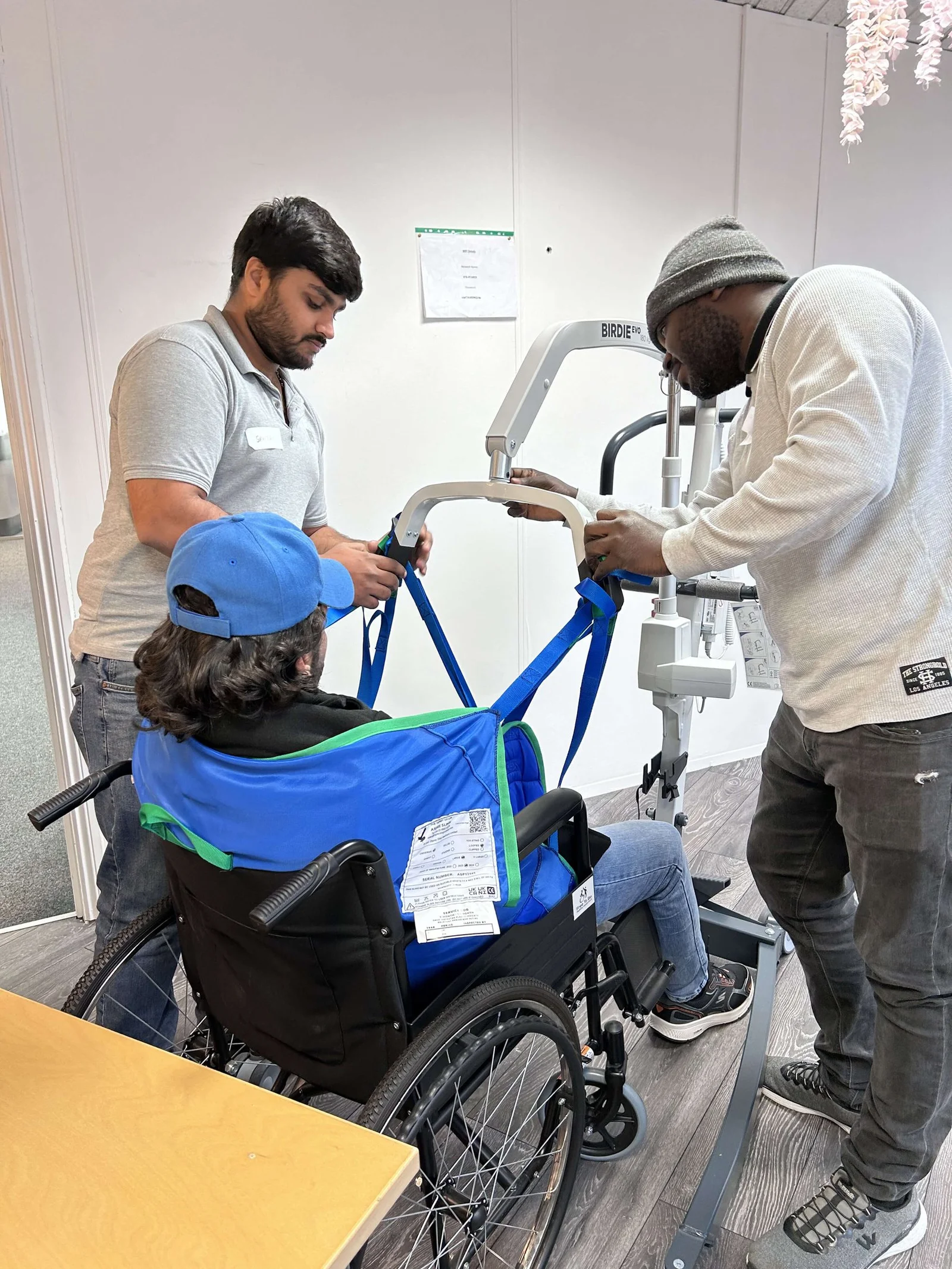 man being listed into a care home hoist